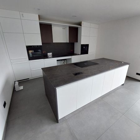 Moderne Kücheninsel mit stilvoller Keramikarbeitsplatte und weißen Schränken.