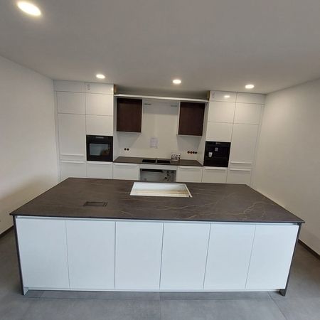 Moderne Kücheninsel mit stilvoller Keramikarbeitsplatte und weißen Schränken.